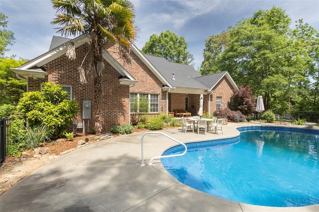 outdoor pool featuring a patio, a diving board, and outdoor dining space