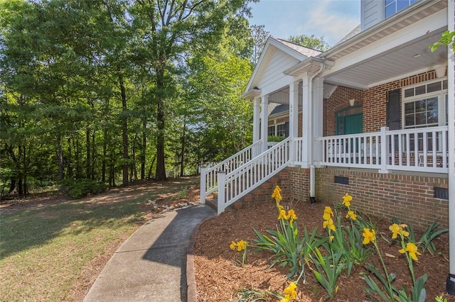 view of side of home with covered porch and brick siding