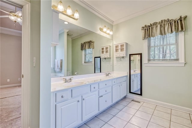 bathroom with crown molding, baseboards, double vanity, and tile patterned flooring