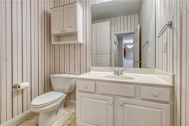 bathroom with wallpapered walls, toilet, vanity, and baseboards