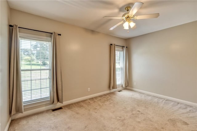 unfurnished room featuring a ceiling fan, light colored carpet, and baseboards