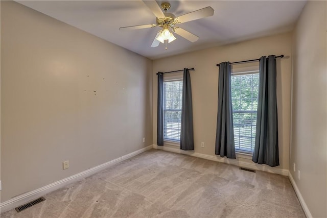 empty room featuring plenty of natural light, ceiling fan, and light colored carpet