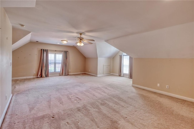 bonus room with a ceiling fan, vaulted ceiling, baseboards, light carpet, and plenty of natural light