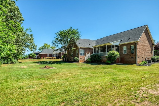 back of property featuring brick siding, a sunroom, and a lawn