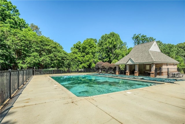 community pool featuring fence, a patio, and view of scattered trees
