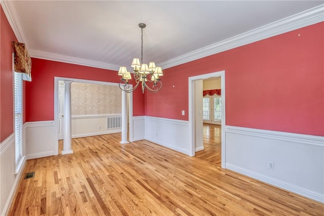 unfurnished dining area with light wood-style flooring, a chandelier, a wainscoted wall, and crown molding
