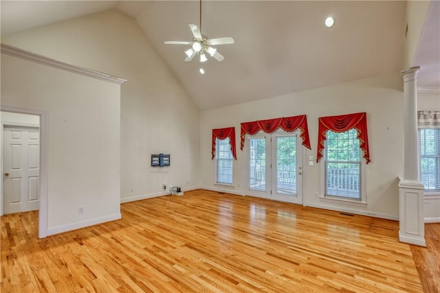 unfurnished living room with high vaulted ceiling, light wood-style floors, a ceiling fan, plenty of natural light, and ornate columns