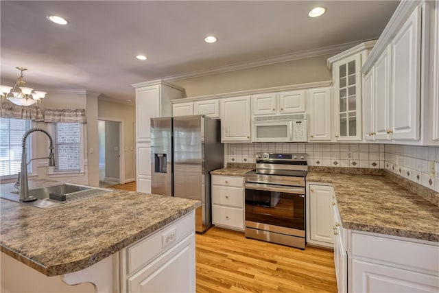 kitchen featuring stainless steel appliances, a sink, crown molding, a chandelier, and white cabinetry