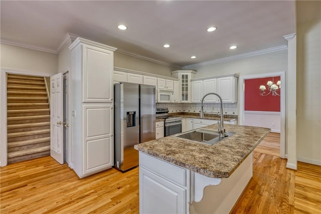 kitchen featuring appliances with stainless steel finishes, a sink, crown molding, white cabinets, and light wood finished floors