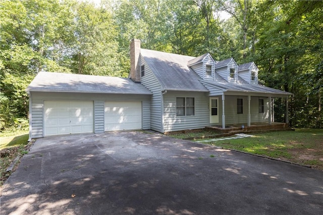 cape cod house featuring asphalt driveway, a garage, a chimney, and covered porch