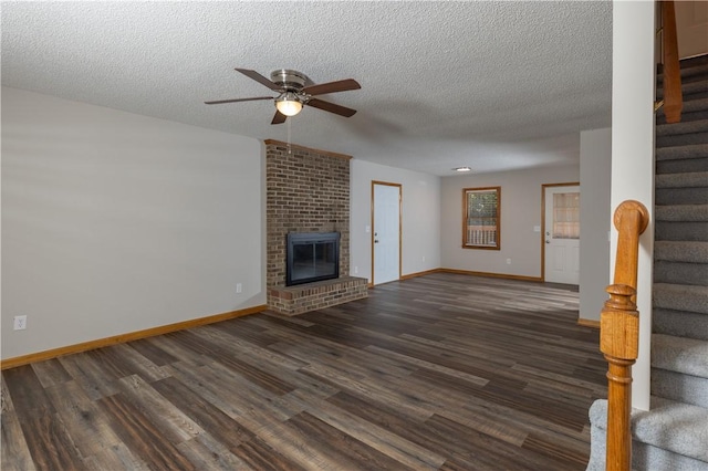 unfurnished living room featuring stairway, ceiling fan, dark wood finished floors, baseboards, and a textured ceiling