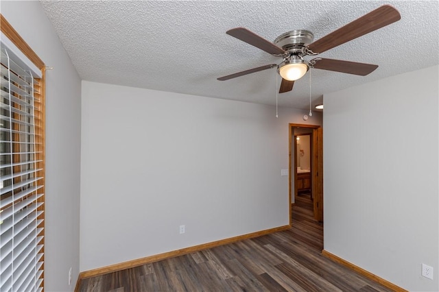 spare room featuring dark wood finished floors, a ceiling fan, a textured ceiling, and baseboards