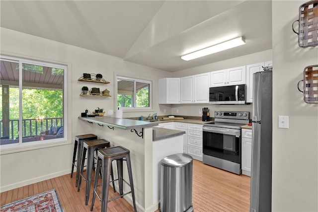 451 Cedar Creek Rd, Sunset, SC 29685 - kitchen with stainless steel appliances, a peninsula, a kitchen bar, white cabinetry, and light wood-type flooring