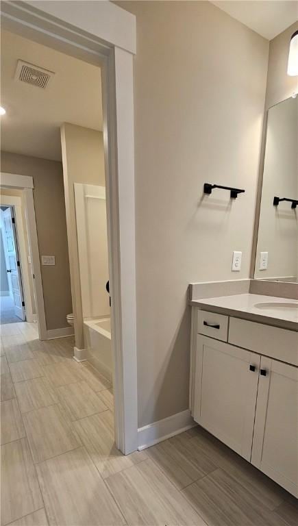 full bathroom featuring toilet, vanity, baseboards, a tub to relax in, and wood finished floors