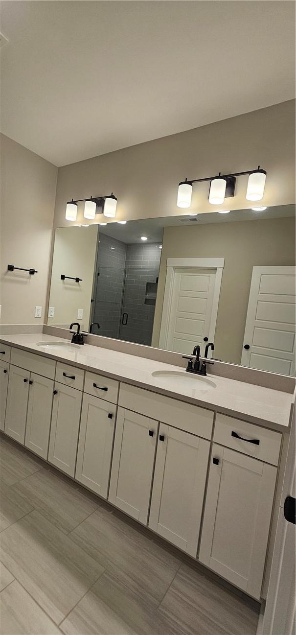 full bath featuring a shower stall, double vanity, and tile patterned floors