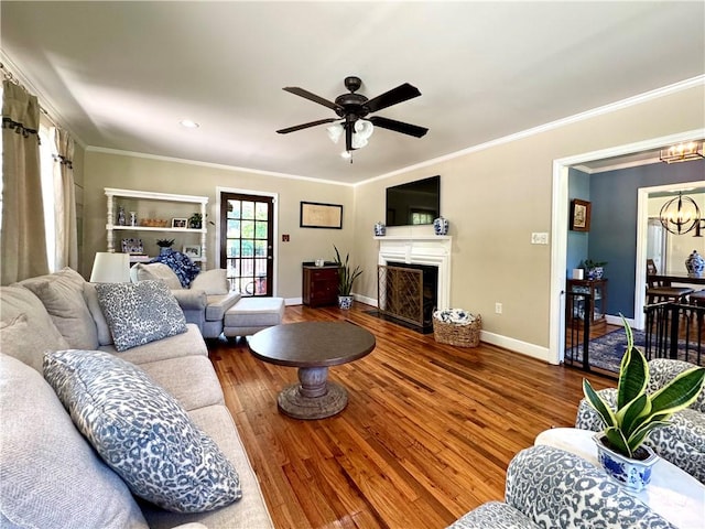 living room with a chandelier, baseboards, wood finished floors, a ceiling fan, and a fireplace with flush hearth