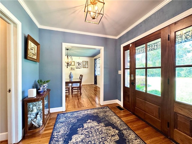foyer featuring a chandelier, wood finished floors, baseboards, and crown molding