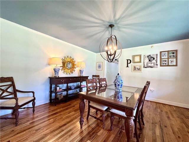 dining space featuring a chandelier, wood finished floors, baseboards, and ornamental molding