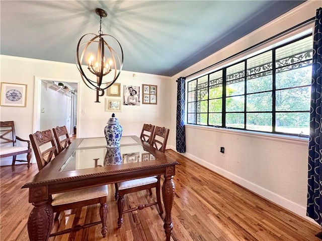 dining space with a chandelier, wood finished floors, baseboards, and crown molding