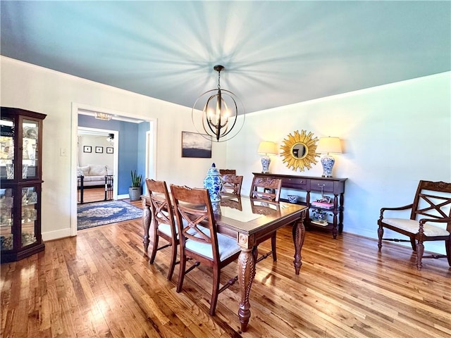 dining area with a chandelier, wood finished floors, and baseboards