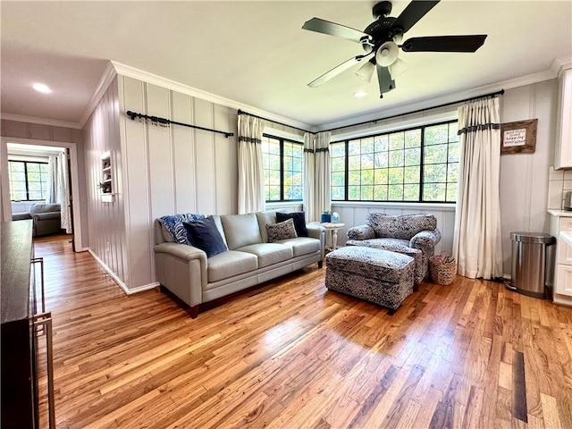 living room featuring ornamental molding, light wood-type flooring, and a ceiling fan