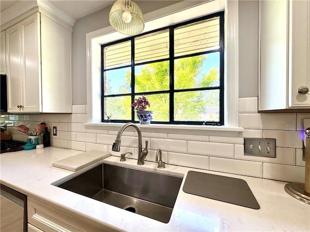 kitchen featuring decorative backsplash, a sink, white cabinetry, and dishwashing machine