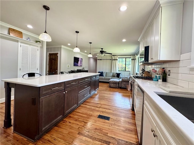 kitchen with a breakfast bar area, dark brown cabinets, open floor plan, ceiling fan, and white cabinetry