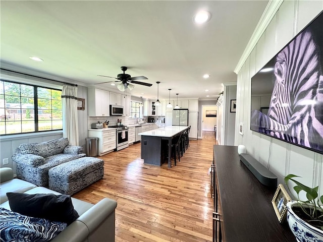living room with a ceiling fan, crown molding, light wood-type flooring, and recessed lighting