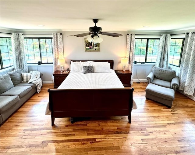 bedroom with baseboards, light wood-style flooring, ornamental molding, and a ceiling fan