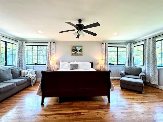 bedroom with multiple windows, wood finished floors, baseboards, and recessed lighting