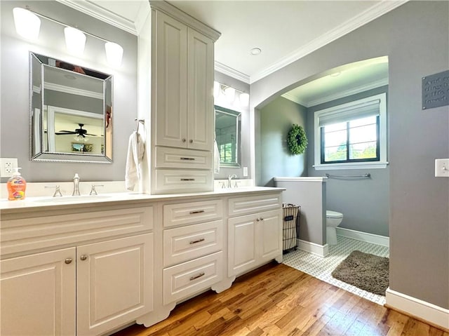 full bathroom with hardwood / wood-style floors, toilet, baseboards, double vanity, and ornamental molding