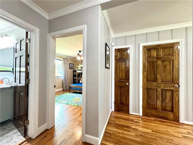 foyer featuring wood finished floors, crown molding, baseboards, and a ceiling fan