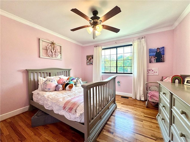 bedroom featuring baseboards, light wood finished floors, crown molding, and a ceiling fan