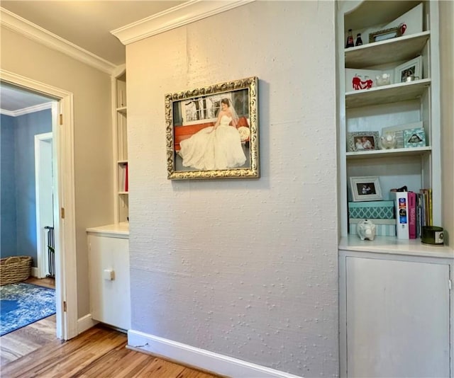 hallway featuring crown molding, light wood-style flooring, and baseboards