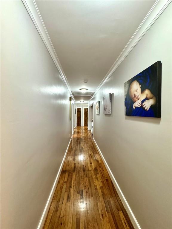 hallway with hardwood / wood-style flooring, baseboards, and crown molding