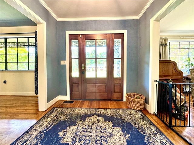 foyer entrance with wood finished floors, baseboards, and ornamental molding
