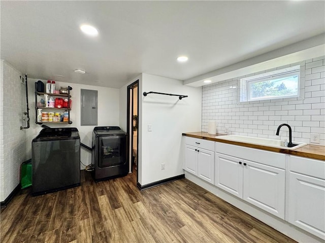 clothes washing area featuring washing machine and clothes dryer, a sink, electric panel, dark wood-type flooring, and recessed lighting