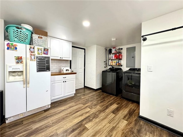 washroom with washing machine and dryer, electric panel, and dark wood-style floors