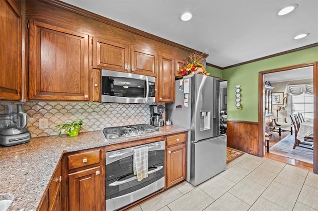 224 Sheffield Rd, Greer, SC 29651 - kitchen with appliances with stainless steel finishes, brown cabinetry, wainscoting, backsplash, and crown molding