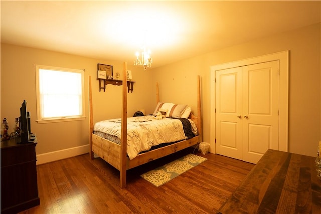 bedroom featuring dark wood-type flooring, a chandelier, and baseboards