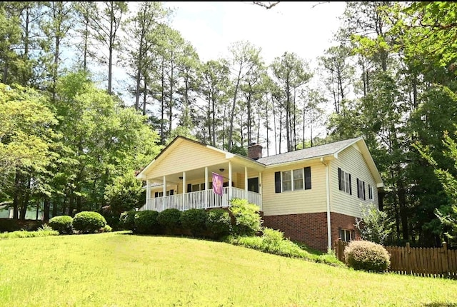 view of front of house featuring a chimney, covered porch, brick siding, and view of scattered trees