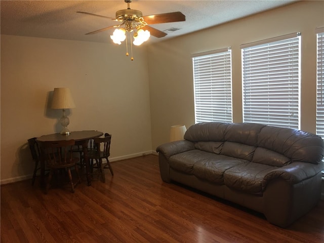 living area featuring wood finished floors, a ceiling fan, baseboards, and a textured ceiling