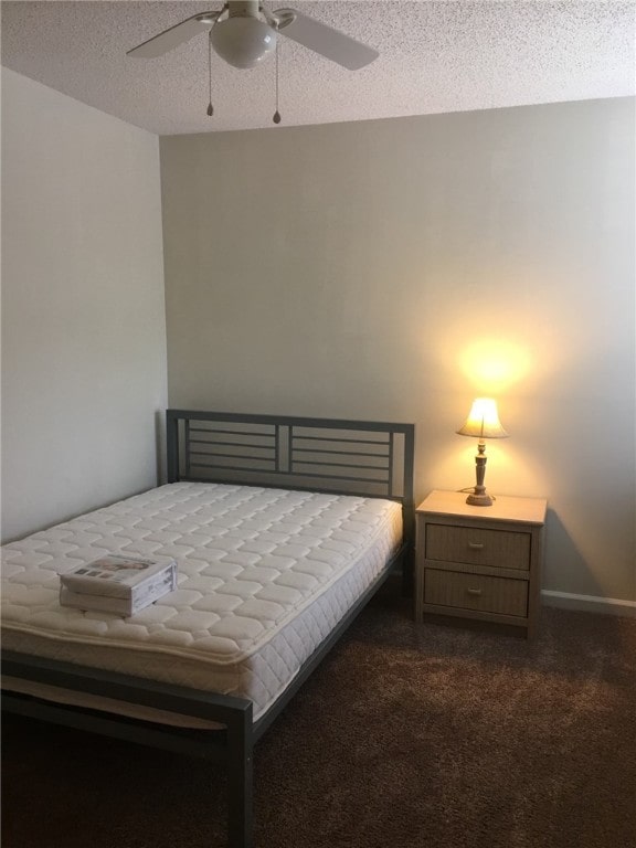 bedroom with dark colored carpet, a textured ceiling, and a ceiling fan