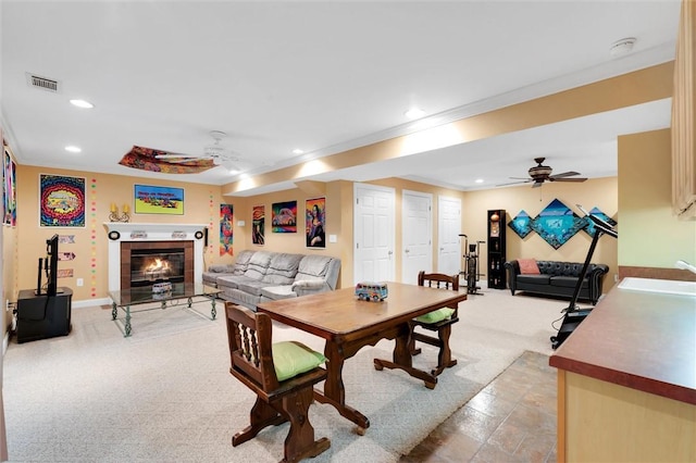 dining space with ceiling fan, recessed lighting, ornamental molding, a tile fireplace, and light carpet