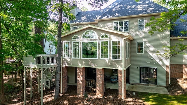 rear view of house featuring a sunroom, a patio area, and a chimney