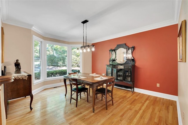 dining room featuring baseboards, crown molding, light wood-style floors, and a fireplace