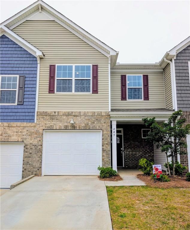 multi unit property with concrete driveway, an attached garage, and brick siding