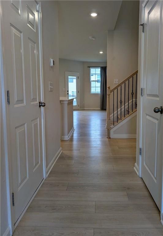 corridor featuring light wood-style flooring, baseboards, stairway, and recessed lighting