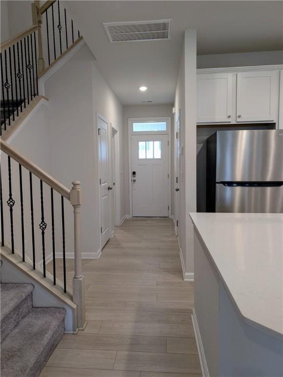 entrance foyer with baseboards, light wood-style flooring, and stairway