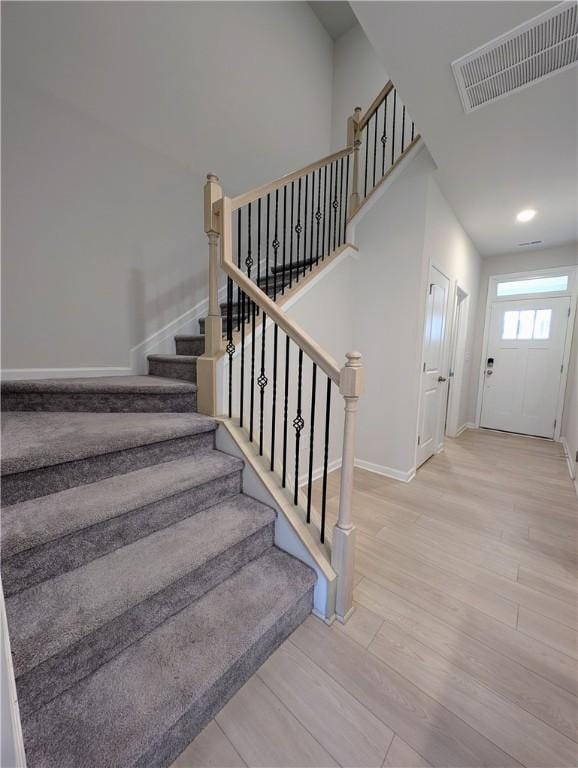 staircase with baseboards, wood finished floors, and recessed lighting